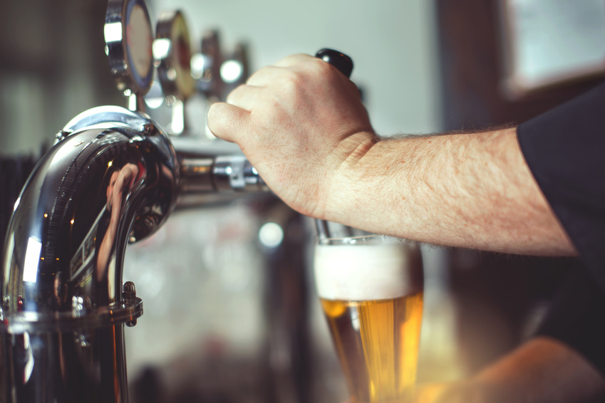 Close-up of a bartender's hands pouring beer from a tap