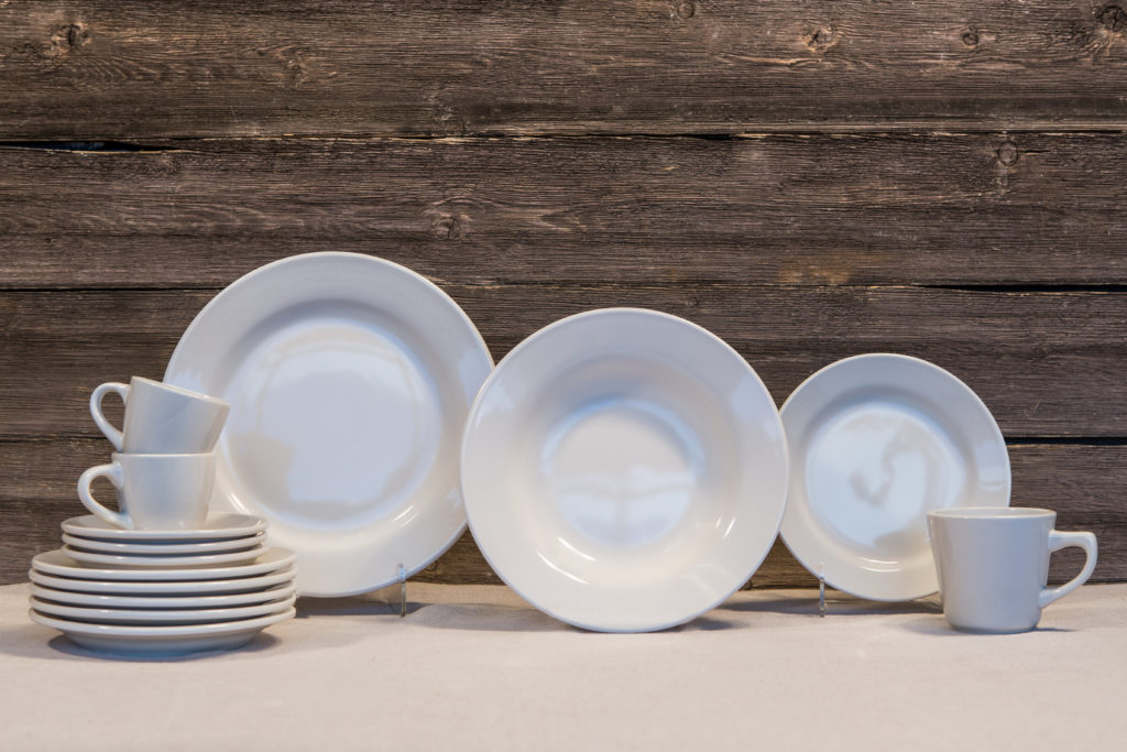Set of white tableware displayed on tablecloth