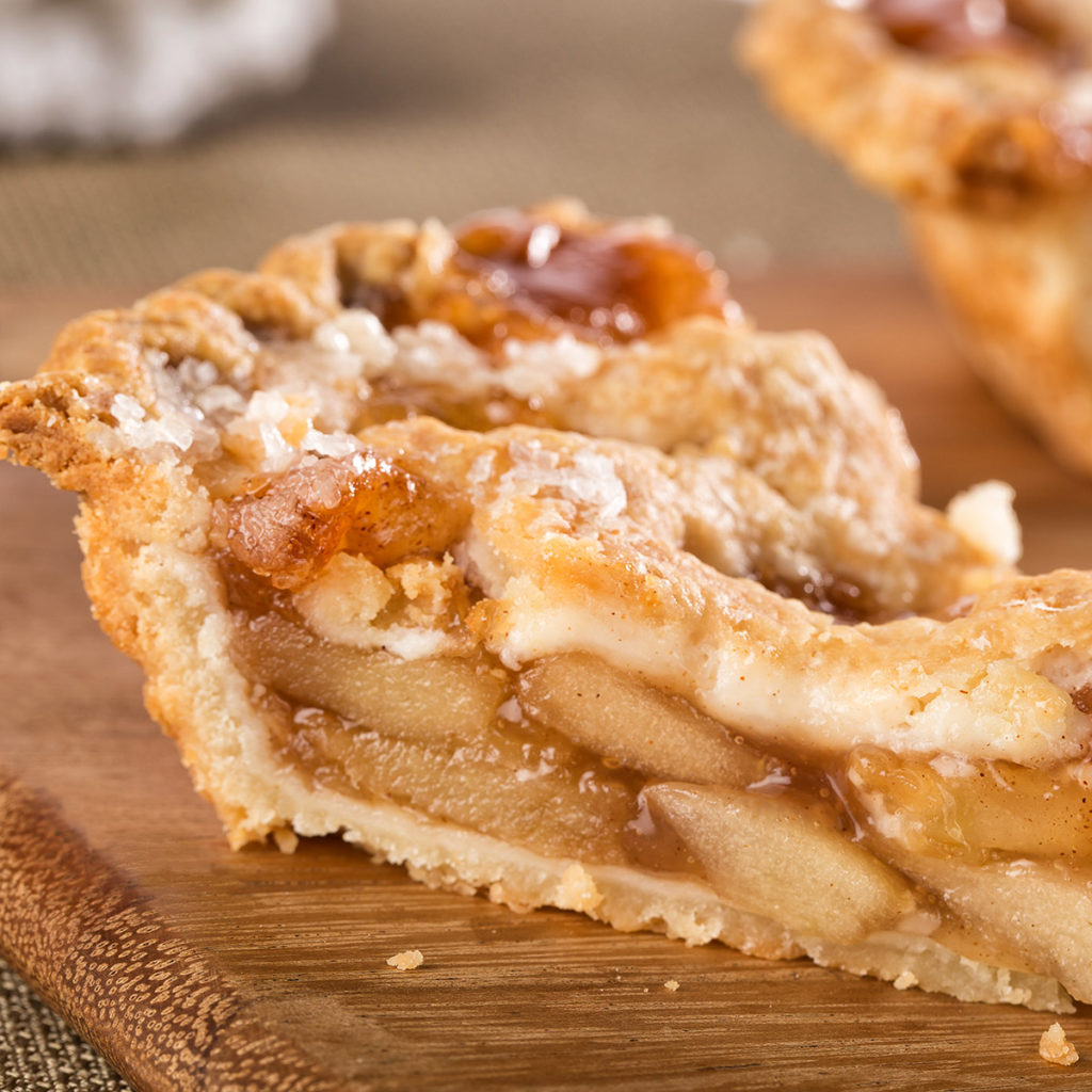 Close up photo of a slice of apple pie from the side showing many layers of apple,
