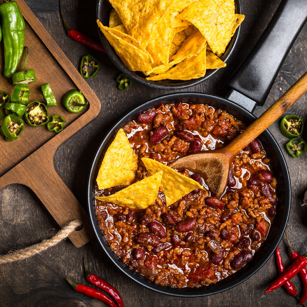 Overhead view of a pan of Chili with Tortilla chips and peppers
